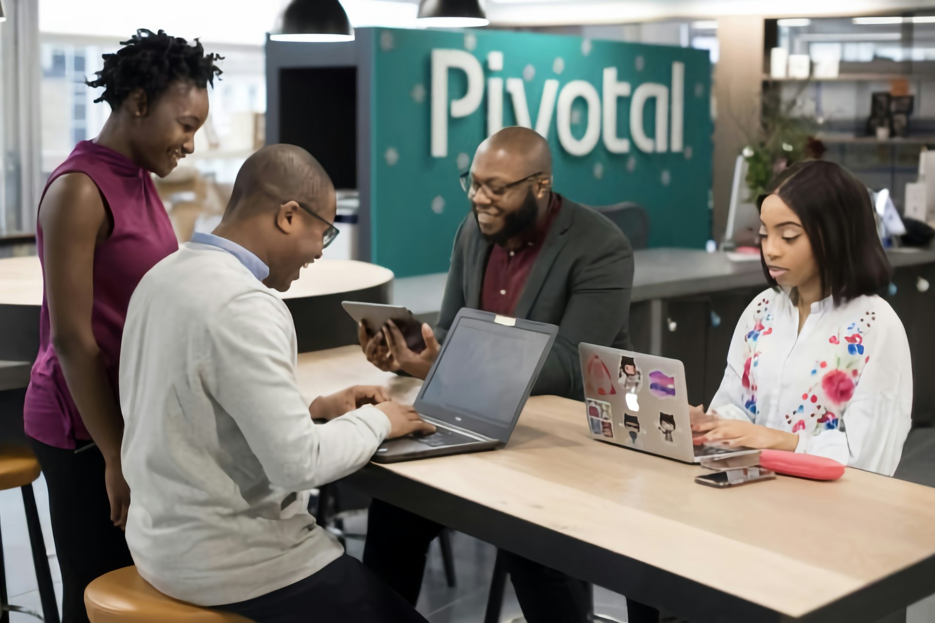 a group of people sitting around a table with laptops